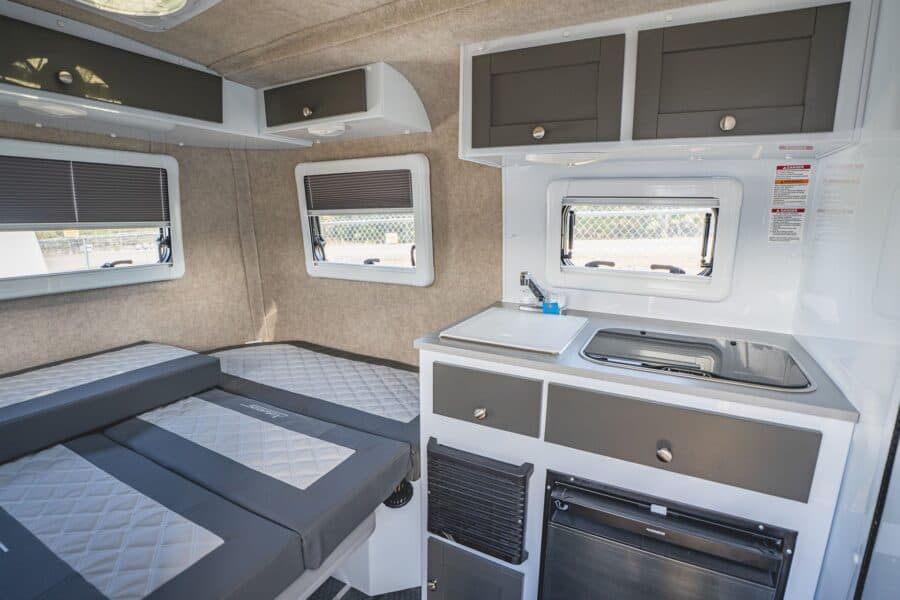 Rear bed with quilted grey cushions and the galley