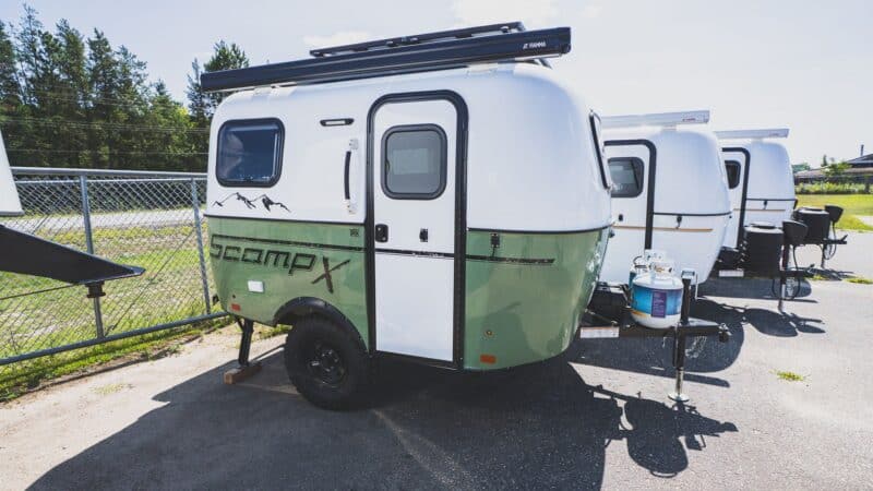 Scamp X with an olive green lower shell and roof rack in a parking lot