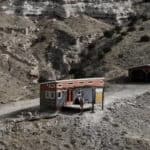 Small tiny house built on land in a rugged, arid landscape with rocky terrain.