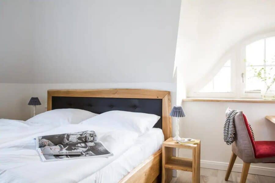 Cozy bedroom in a 387 sq. ft. German cottage guesthouse with minimalist decor and natural light.