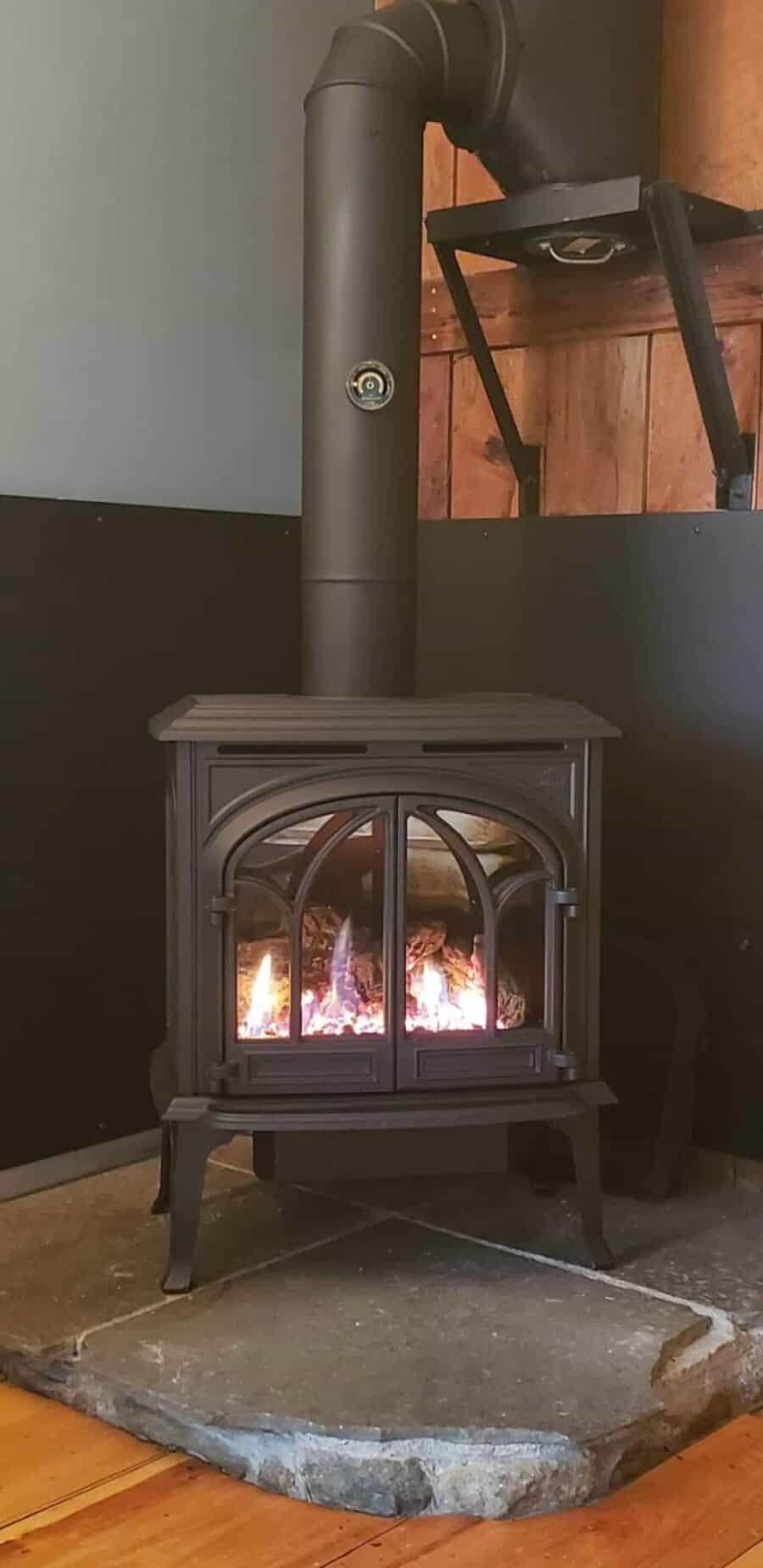 Small Vermont cabin fireplace with a wood stove and stone base.