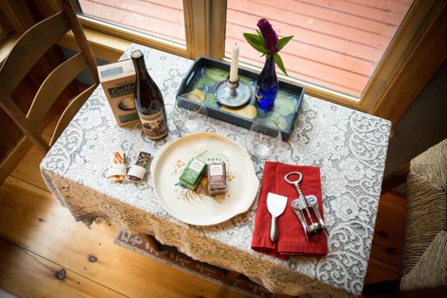 Intimate cabin table set with wine, snacks, and candles in a Vermont retreat.