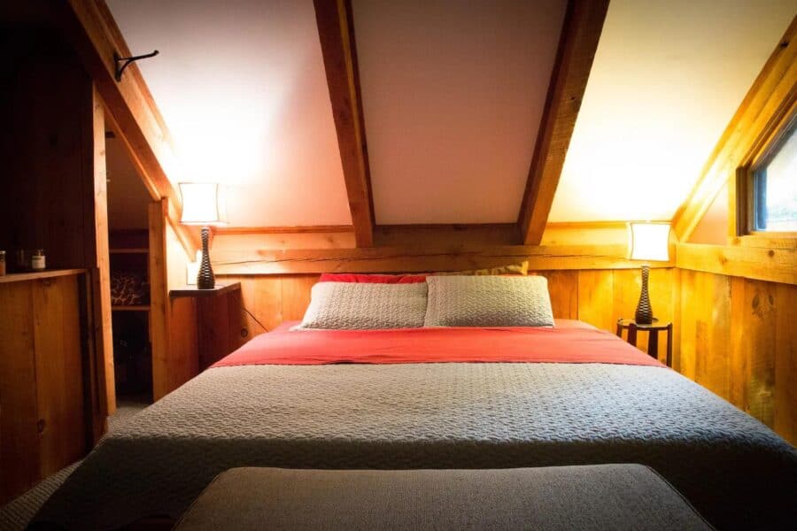 Warm rustic bedroom in a romantic Vermont cabin with wooden accents and soft lighting.