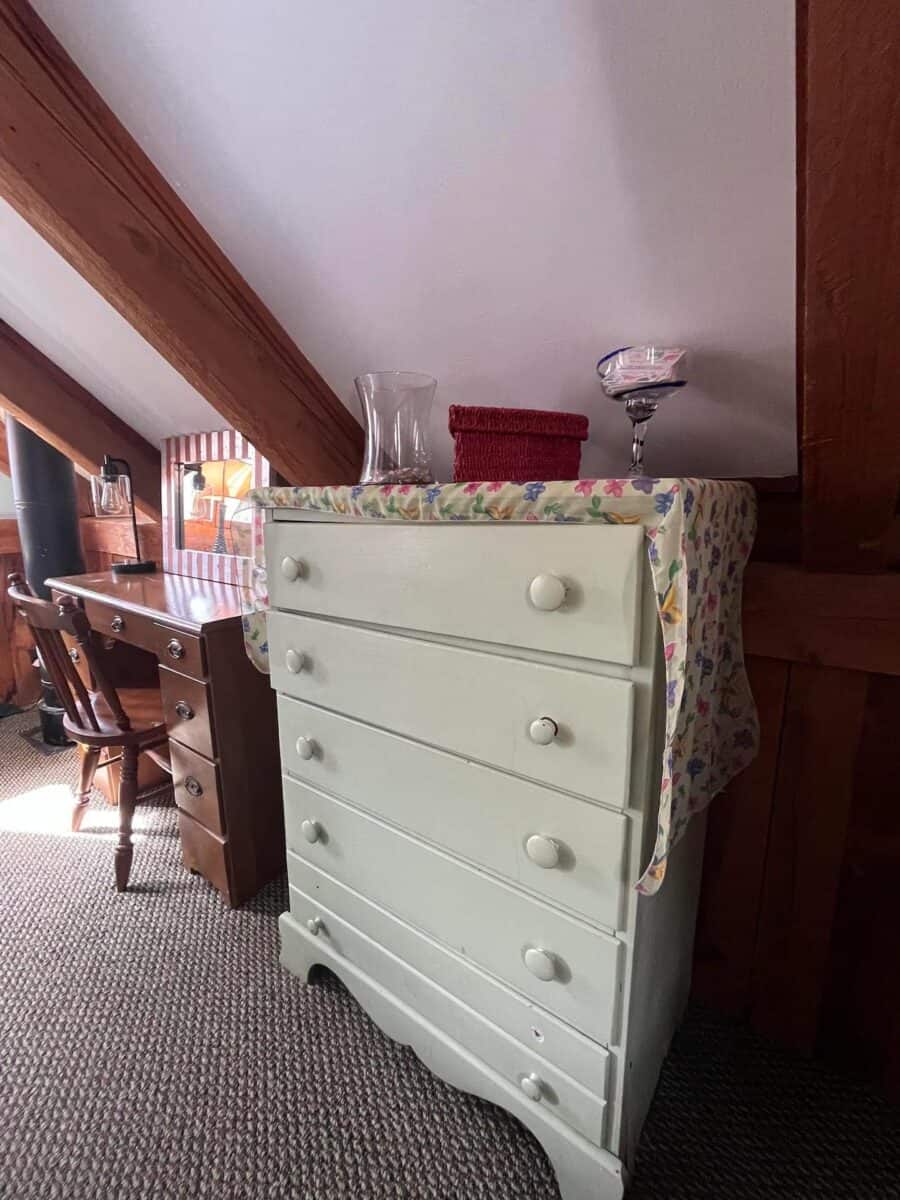 Vintage white dresser with colorful cloth cover in rustic Vermont cabin.