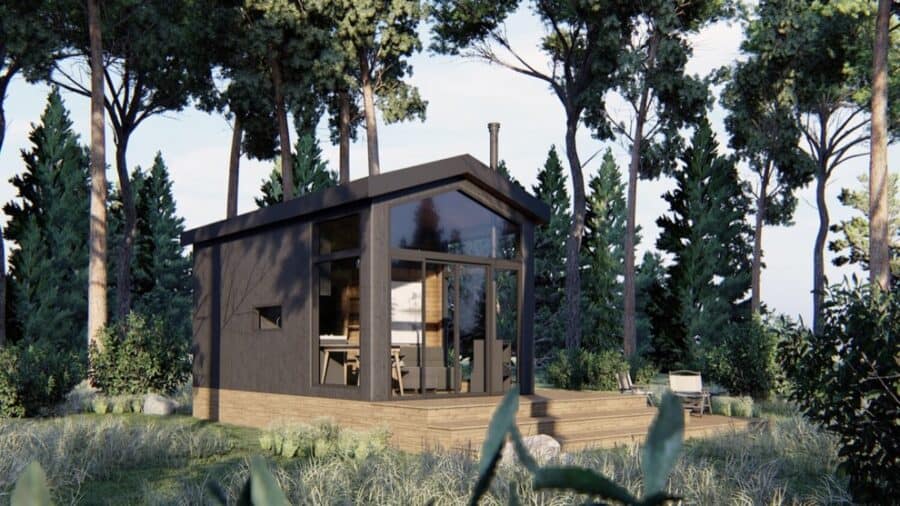 Small ShadowPine cabin with large glass windows in a forest setting.