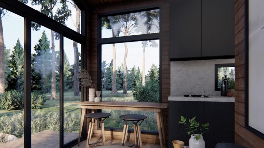 Bright tiny house interior with expansive glass windows overlooking nature.