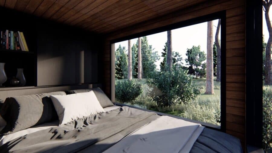 Bright interior of a tiny house bedroom with large window and natural wood accents.