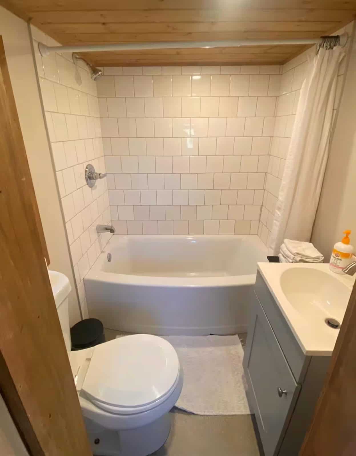 Full bathroom in the Shiva tiny home with a subway-tiled tub-shower, vanity, and flush toilet