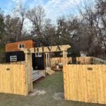 Shiva tiny home exterior with cedar and black board-and-batten siding and a SHIVA entrance arch over a private fenced yard