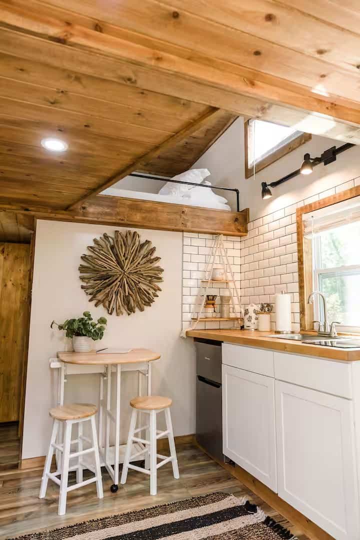 Shiva tiny home kitchen with white subway tile and butcher block counters below a sleeping loft