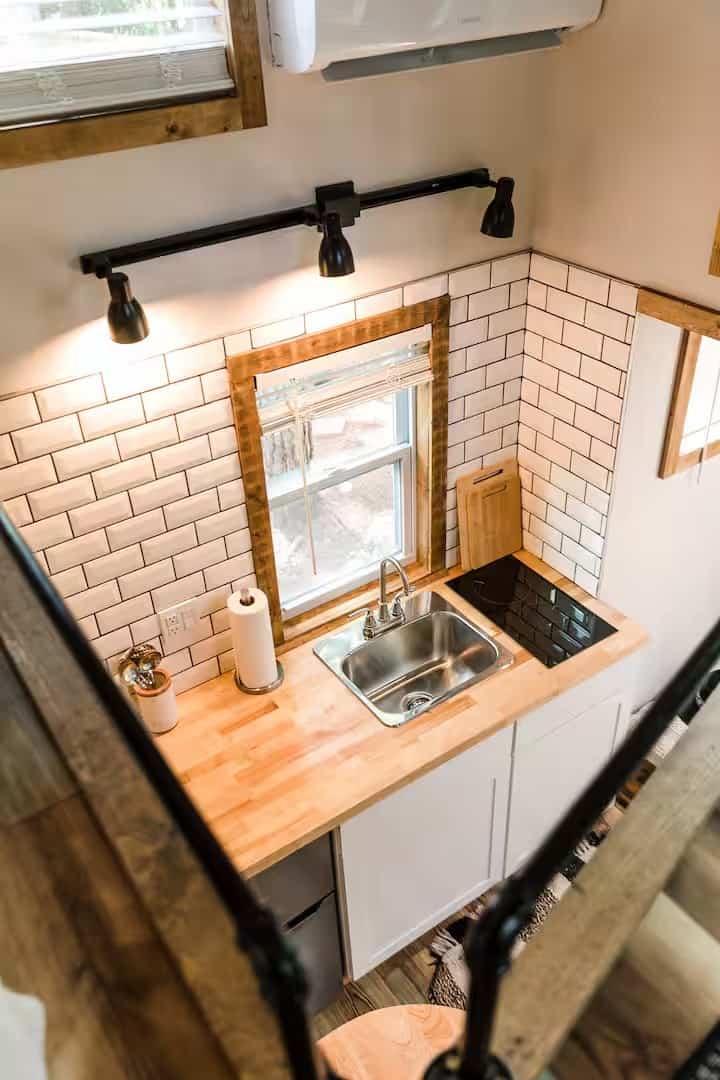 Kitchenette in the Shiva tiny home with a stainless sink, electric cooktop, and butcher block counter