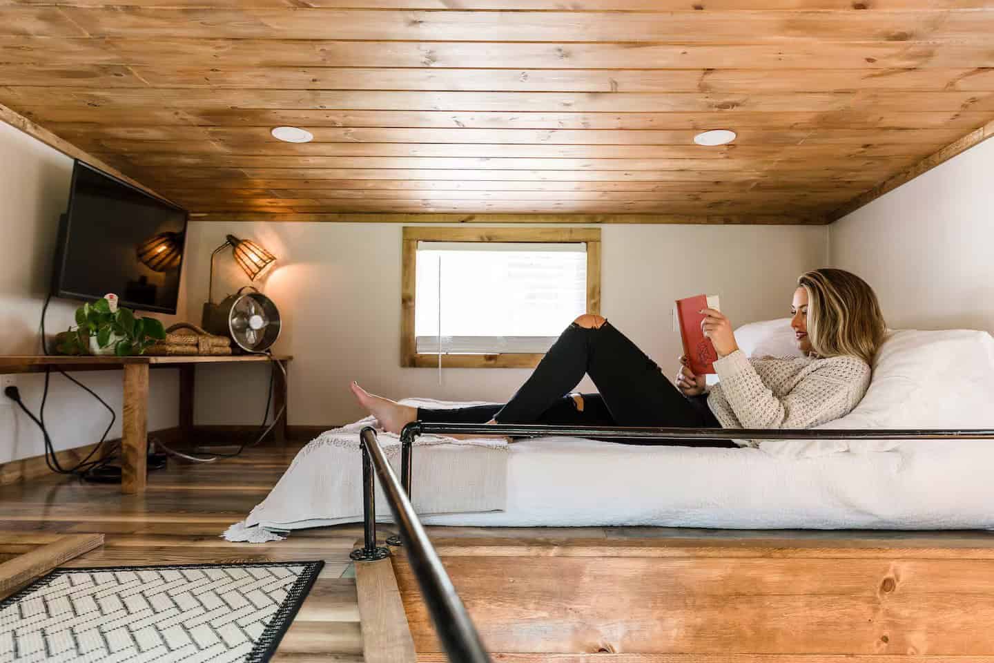 Sleeping loft in the Shiva tiny home with a smart TV and a bright window