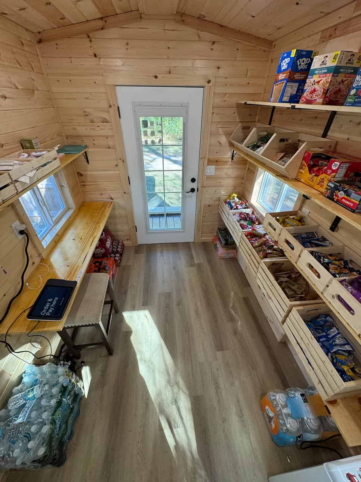 Inside the Simplify Further tiny store with an order-and-pay tablet and shelves of snacks and drinks