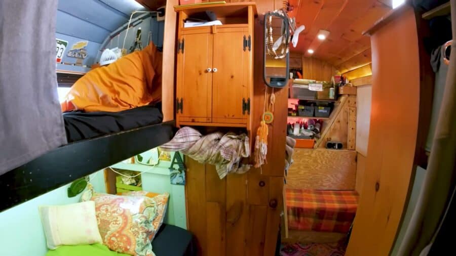 Compact skoolie interior with sleeping and storage space for a family adventure.
