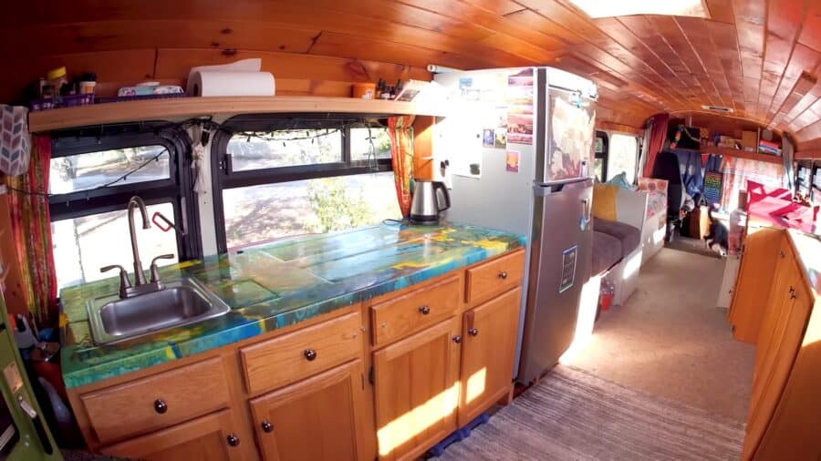 Cozy tiny house kitchen with wooden cabinets and compact appliances.