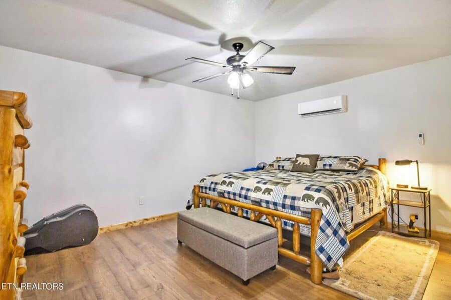 Interior of a tiny house bedroom featuring a wooden bed frame, ceiling fan, and minimalist decor.