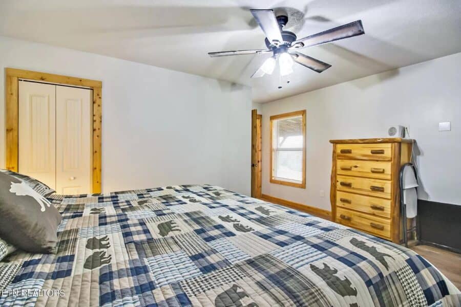 Cozy tiny house bedroom with wooden furniture and ceiling fan.