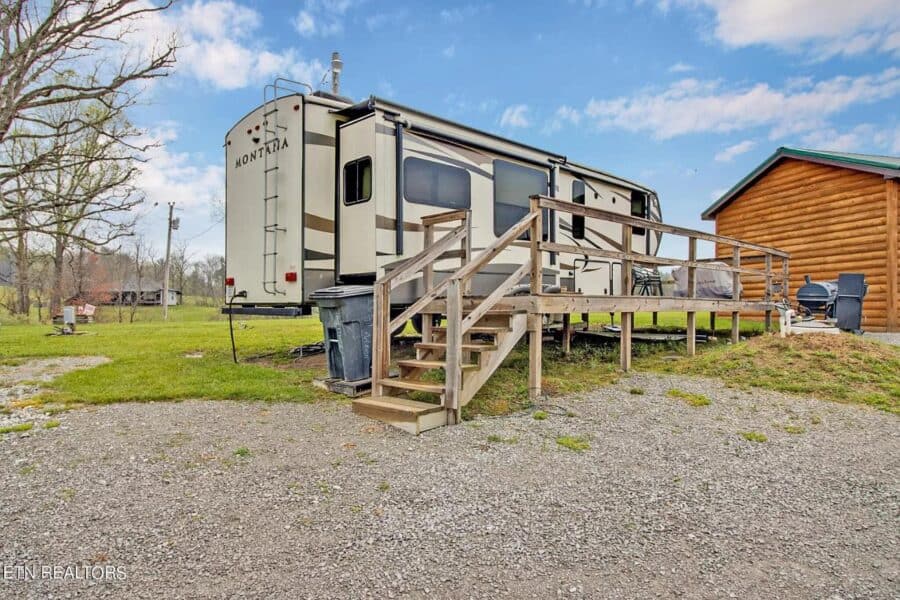 Portable tiny house with deck and hookups in rural Tennessee setting.