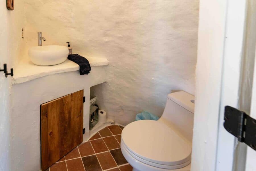 Small rustic bathroom in a tiny house with white textured walls and a compact toilet.