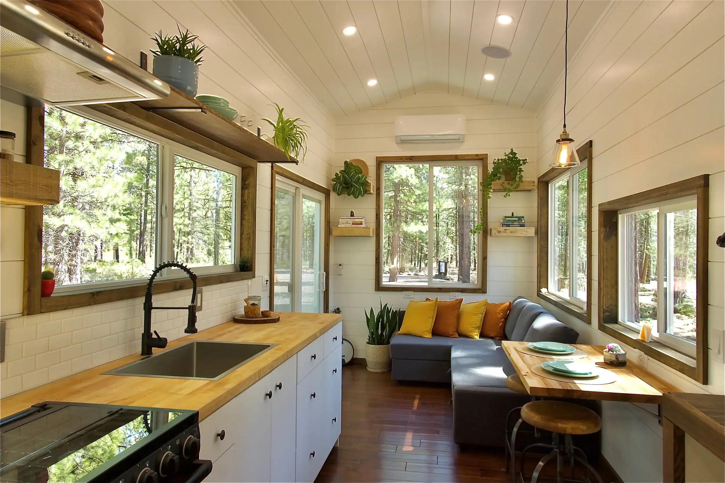 Bright, plant-filled Spindrift Homes tiny house interior with natural light and comfortable furniture