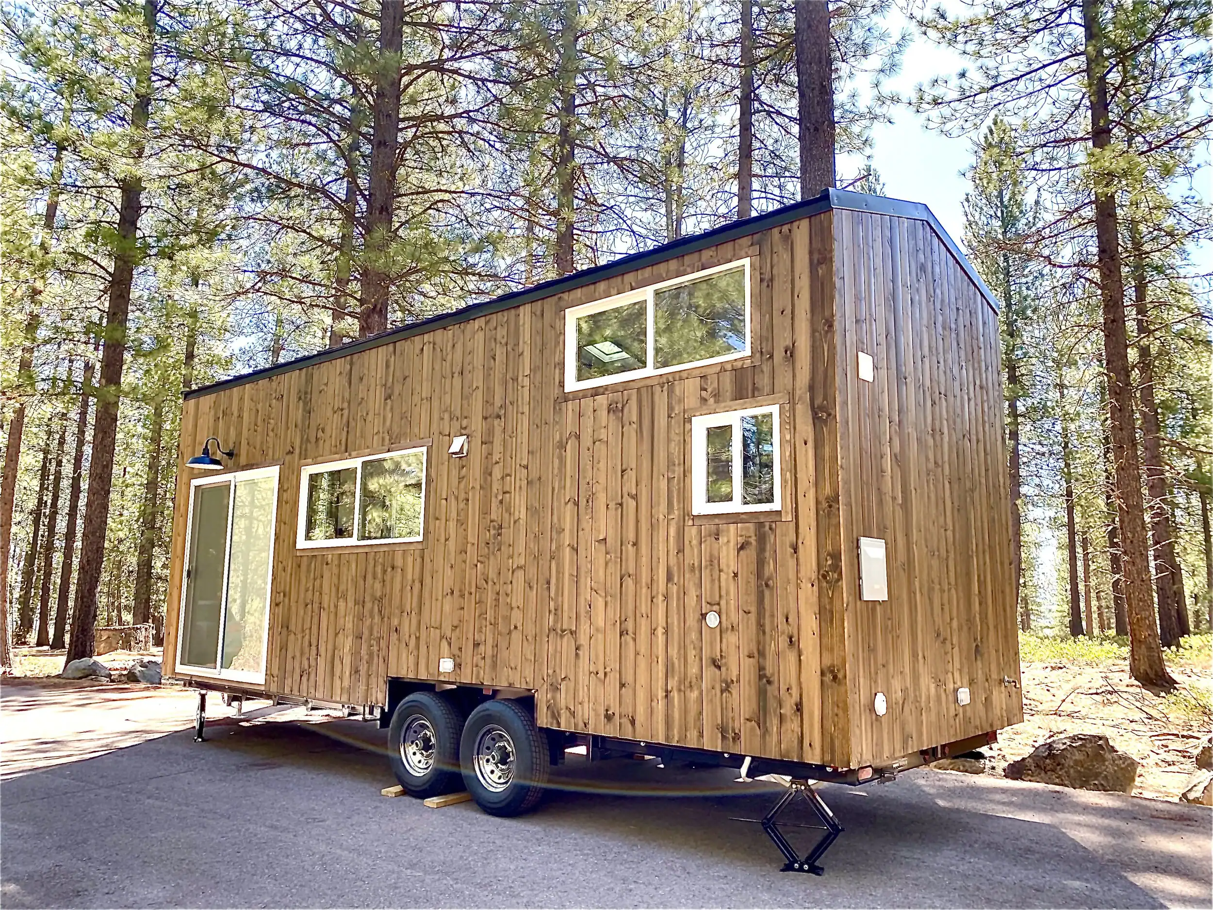Spindrift Homes custom tiny house on wheels with wood paneling parked among the trees