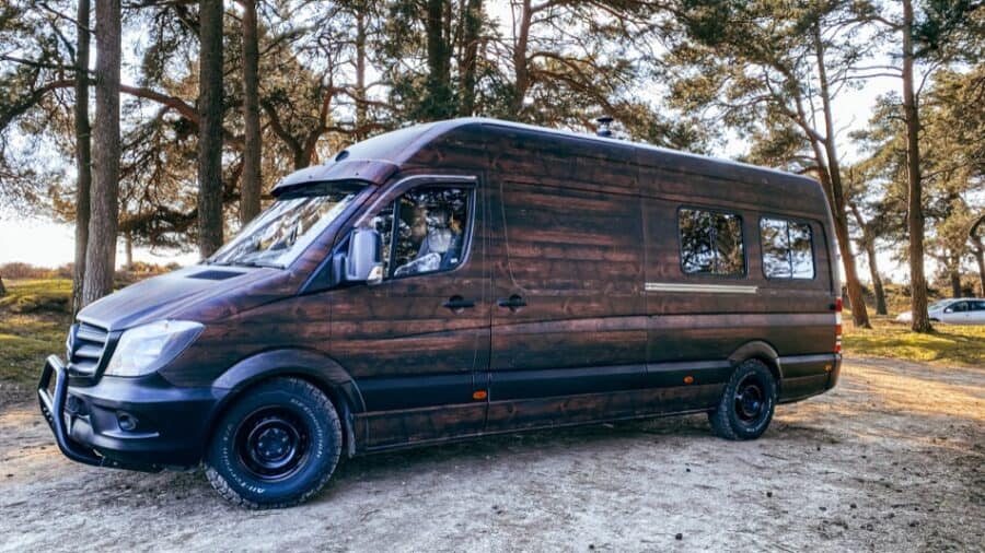 Rustic wooden campervan parked in a scenic outdoor setting.