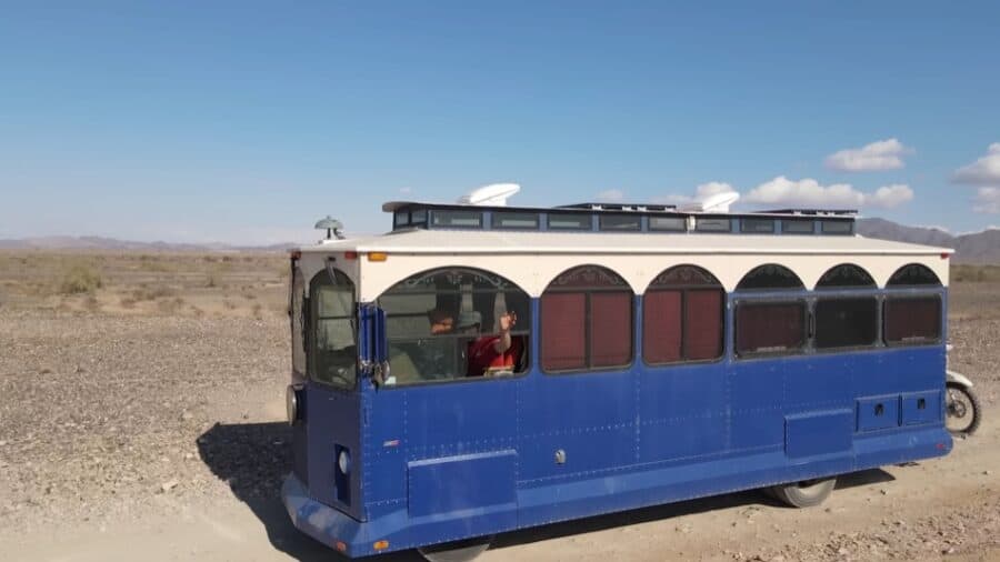 Historic trolley converted into a stylish tiny home in a desert landscape.