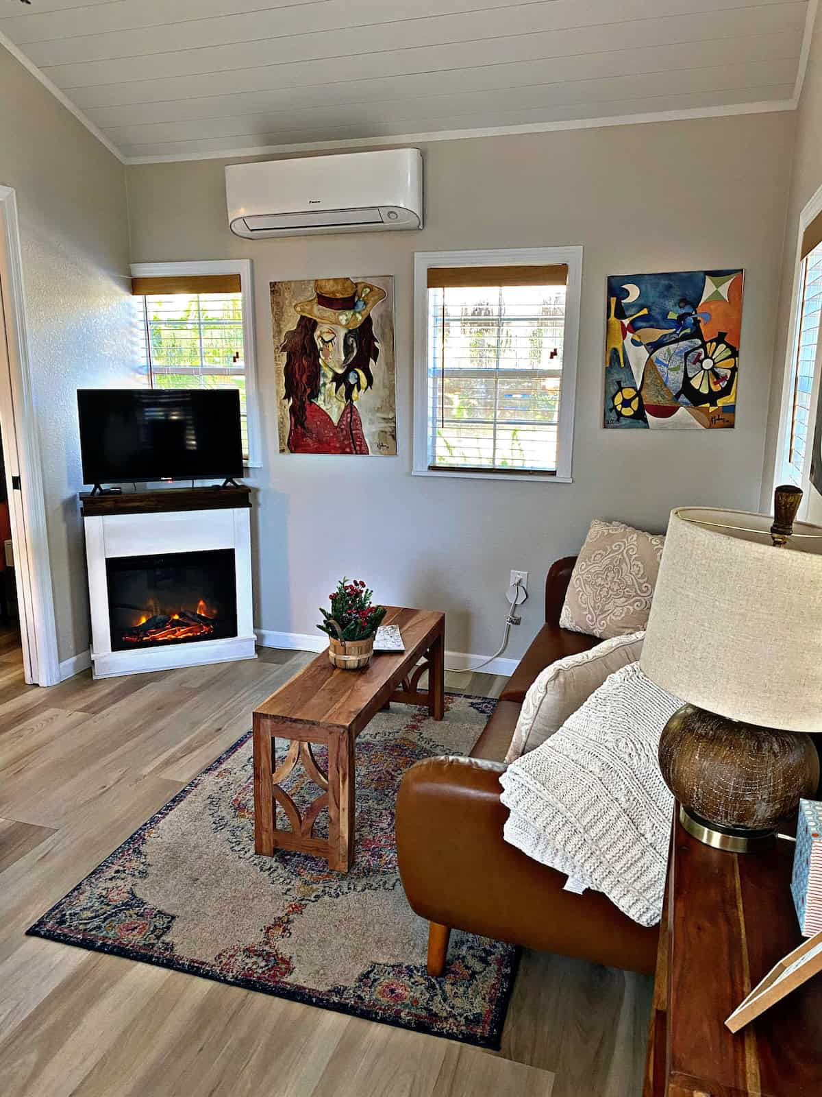 Charming tiny house living room featuring colorful artwork, a fireplace, and comfortable seating. Pe.
