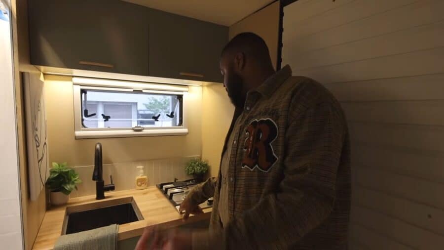 Compact tiny house kitchen with modern appliances and natural light.