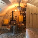 Cozy interior of a tiny stone cellar cottage in France, featuring rustic wooden furniture and warm l.