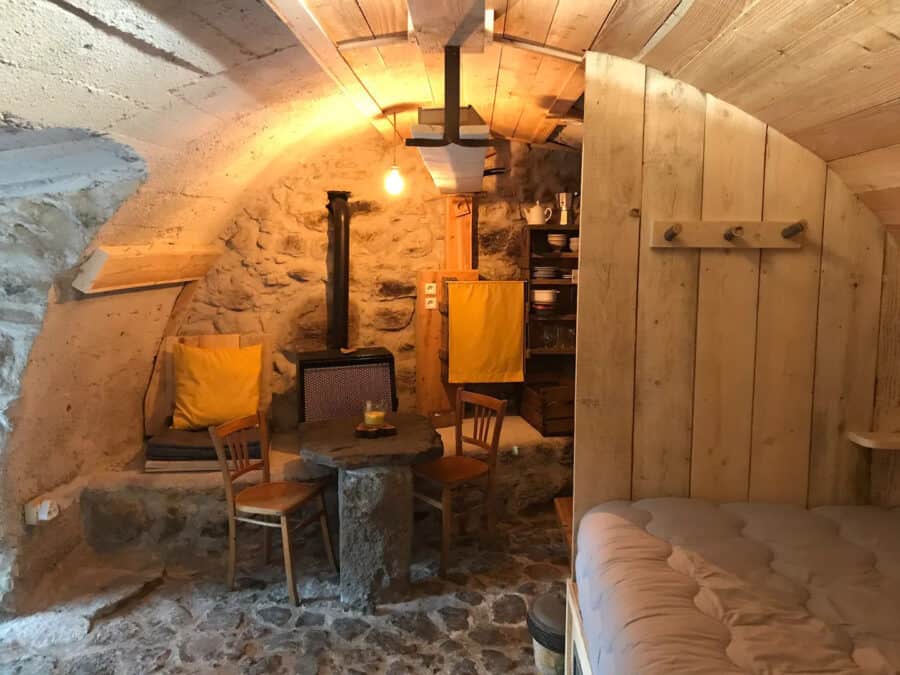 Cozy interior of a tiny stone cellar cottage in France, featuring rustic wooden furniture and warm l.