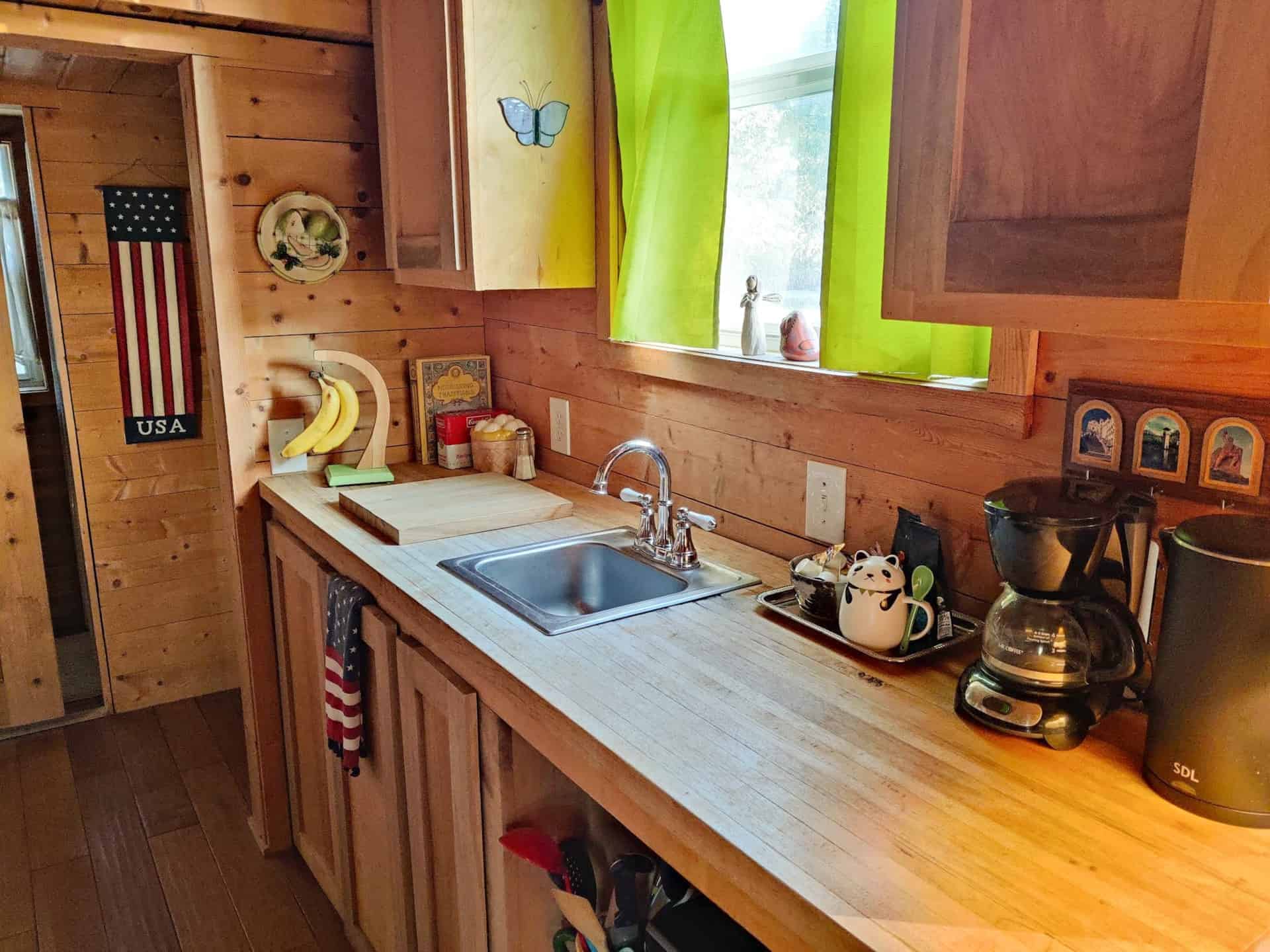 Kitchen with butcher block countertops, stainless sink, and green curtains