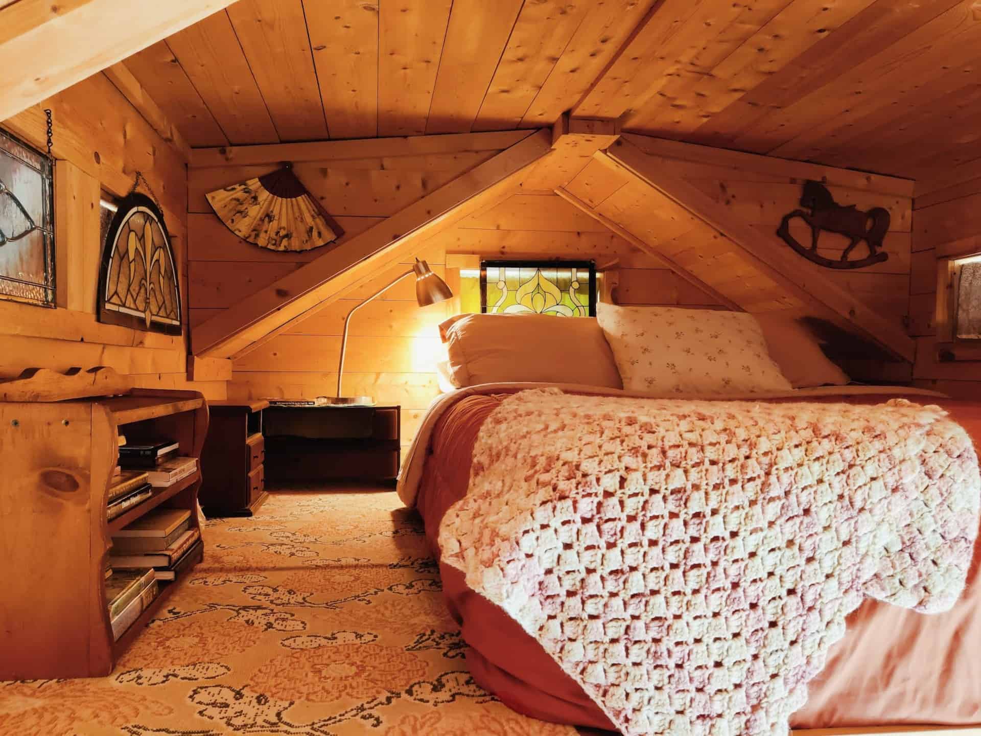 Loft bedroom with vaulted pine ceiling and antique stained-glass windows