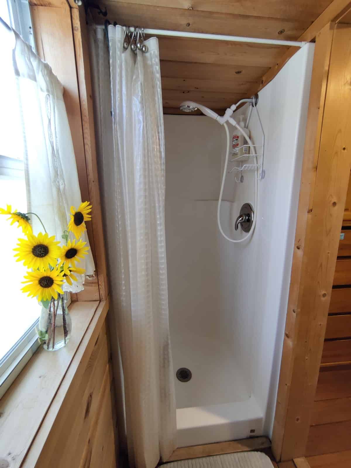 Walk-in fiberglass shower stall in the pine-lined bathroom