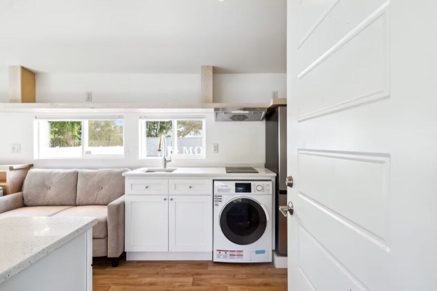 Compact tiny house kitchen with modern appliances and bright natural light.