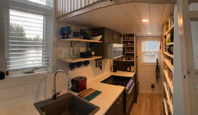 Compact tiny house kitchen with modern appliances and ample storage space.
