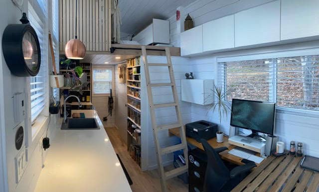 Interior view of a compact tiny house with a loft, workspace, and modern decor.