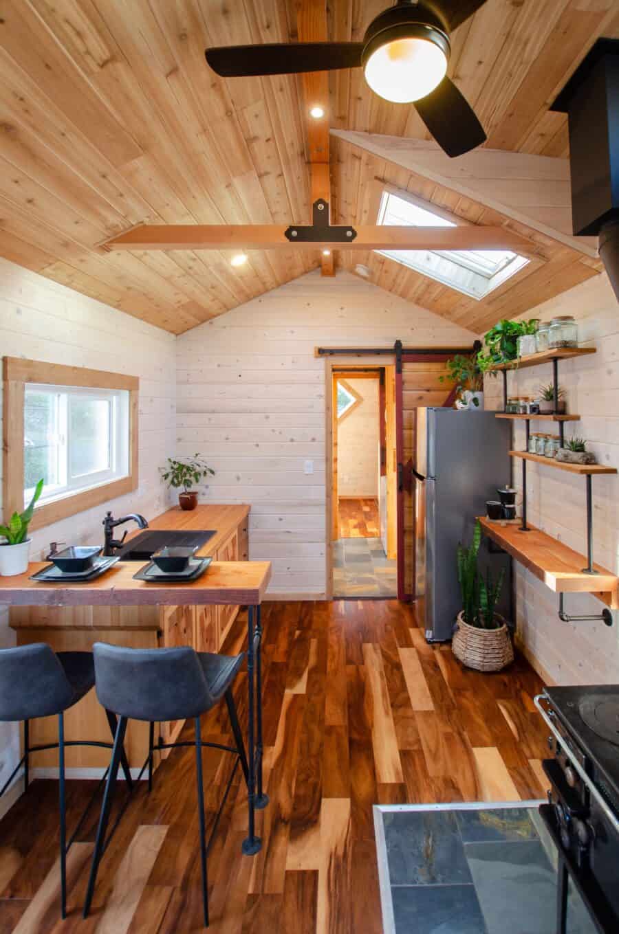 Bright tiny house kitchen with skylight and wooden accents.