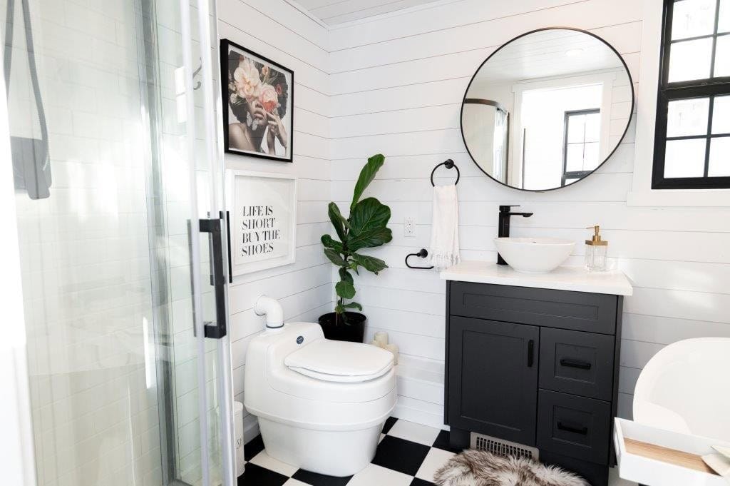 Glass shower enclosure, composting toilet and round mirror in the Daphne's black and white bathroom