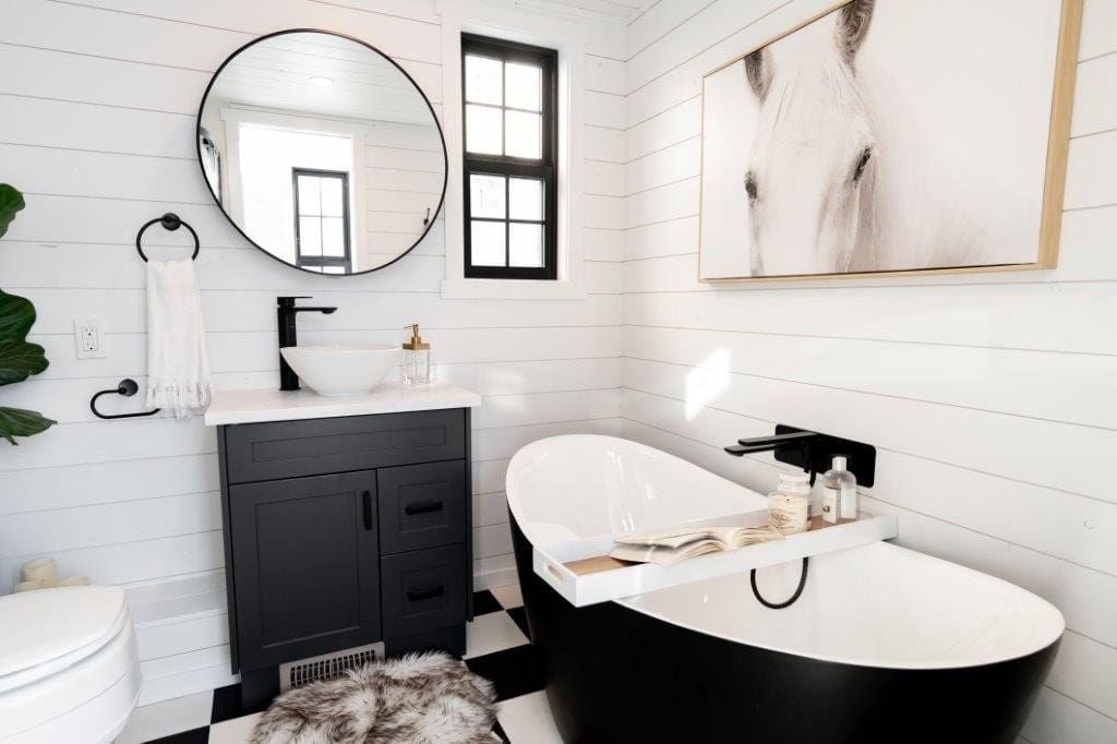 Black freestanding soaking tub, black vanity with vessel sink and checkerboard tile floor in the Daphne bathroom