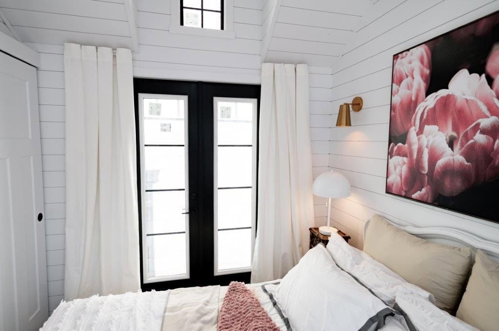 Black French doors with transom window at the foot of the bed in the Daphne bedroom