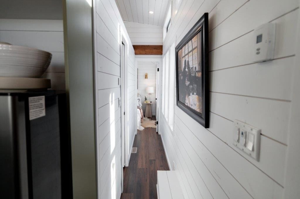 Shiplap hallway with dark laminate flooring leading from the kitchen to the Daphne's main-floor bedroom