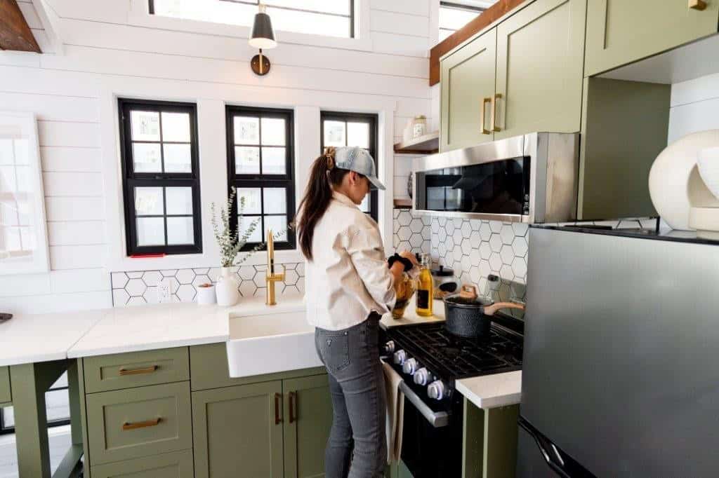 Sage green shaker cabinets, hexagon tile backsplash, apron-front farmhouse sink and brass faucet in the Daphne kitchen