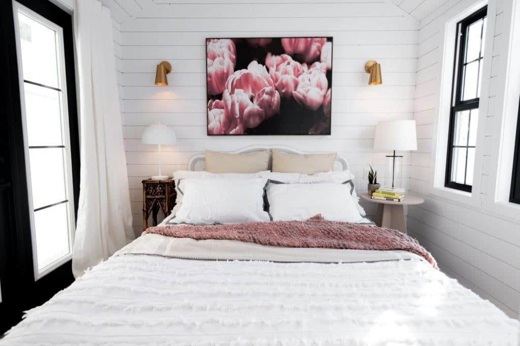 Queen bed with brass sconces and windows on both sides in the Daphne's main-floor bedroom