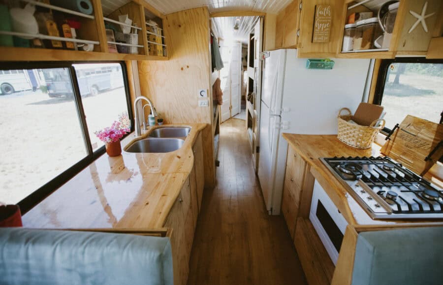 Cozy tiny house kitchen with wooden cabinets, sink, and stove.