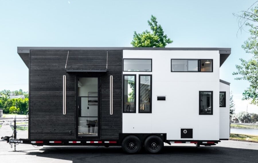 Tiny house on trailer with sleek black and white exterior design.