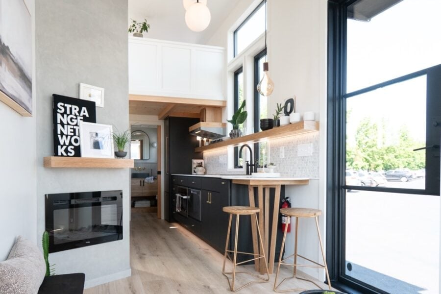Modern tiny house kitchen with sleek black cabinets, wooden accents, and ample natural light from la.