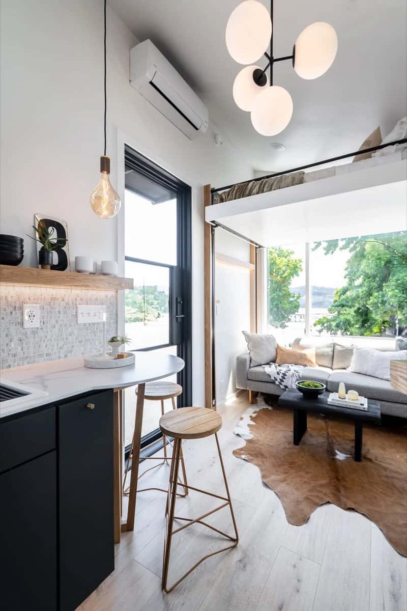 Round marble bar table with wood stools beside the kitchen in the Terra Urban tiny house