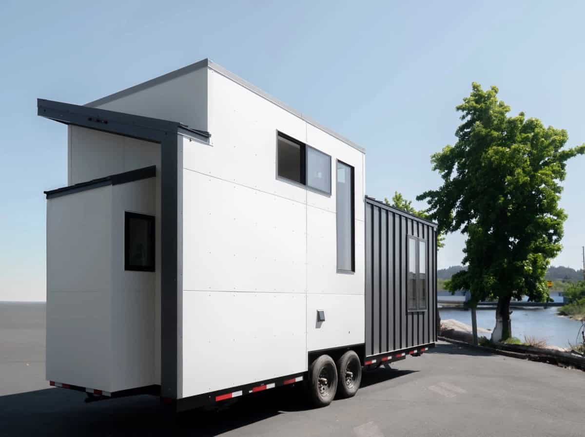 Rear three-quarter view of the Terra Urban tiny house on wheels parked near the water