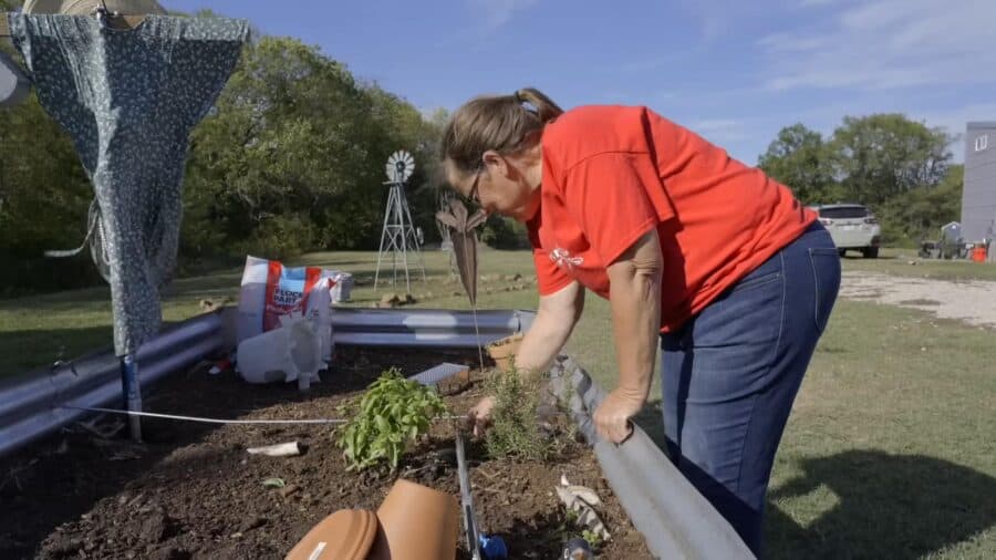 Woman planting a small garden in a tiny house backyard.